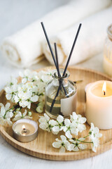 Obraz na płótnie Canvas Home comfort, coziness, aromatherapy. Cozy interior with knitting, burning candles and aroma perfume diffuser in the living room. Fresh spring blossom fragrance, apple cherry flowers.