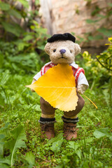 Huge Beautiful Fall Leaf / Adorable dressed teddy bear with beret hat hold first yellow poplar leaf of autumn season (copy space)
