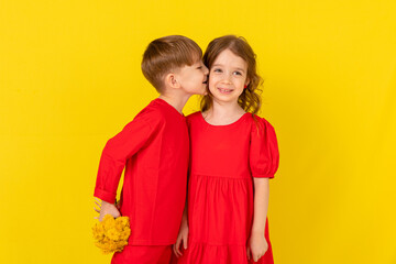 First love. A little boy gives flowers to a little girl and kisses her cheek.