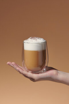 Hand hold ice latte coffee in a glass with cream on bottom 