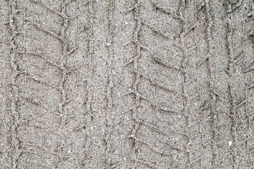 Car tire print on gray sand close-up