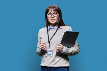 Middle aged woman with educational center badge, laptop on blue background
