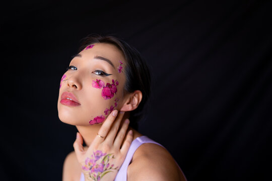 Young Asian lady with painted flowers on face in studio
