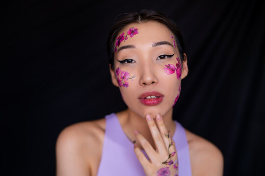 Young Asian lady with painted flowers on face in studio