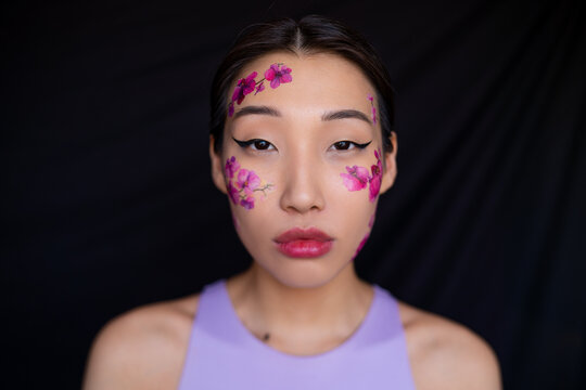 Young Asian lady with painted flowers on face in studio