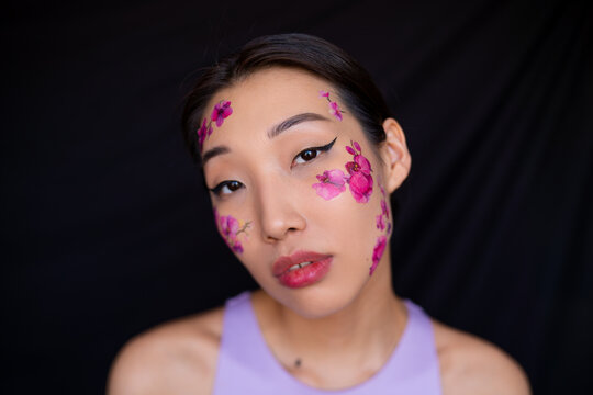 Young Asian lady with painted flowers on face in studio