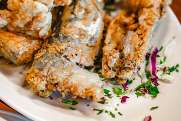 Fish fried in batter on a white platter, selective focus