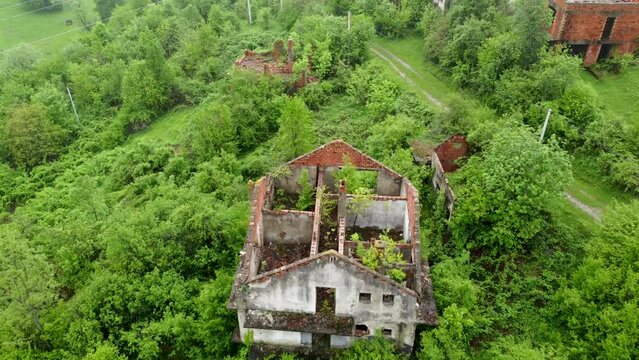 Aerial drone view of ruined and damaged house in village as war aftermath in Bosnia and Herzegovina. Houses destroyed and burned by artillery during the war . Abandoned buildings. Houses in ruins. 