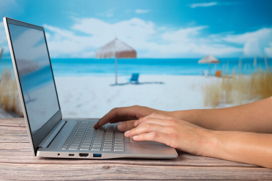 Person working on computer, with out-of-focus background beach.