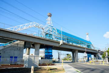 Modern elevated light rail station spanning a urban road on a clear autumn day - obrazy, fototapety, plakaty