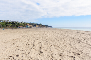 Large sandy beach along the coast of California on a partly cloudy autumn day