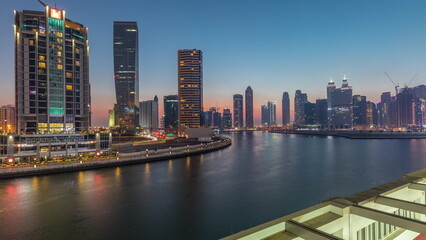 Obraz premium Modern city architecture in Business bay district. Panoramic view of Dubai's skyscrapers day to night timelapse