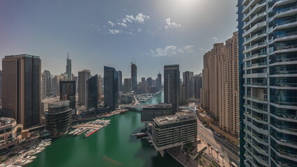 Aerial view to Dubai marina skyscrapers around canal with floating boats all day timelapse