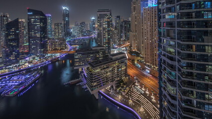 Aerial view to Dubai marina skyscrapers around canal with floating boats night timelapse