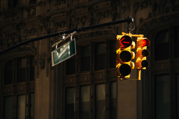 Yellow American traffic light lit by the sun hanging above the road