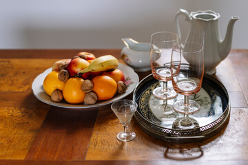 Fruit plate, glasses on tray, ceramic pitcher and a sauce pan on table
