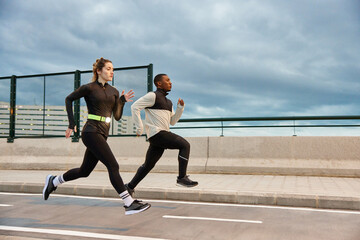 Active sportspeople running on track on city street