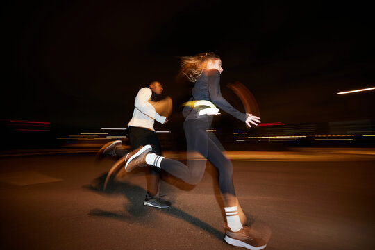 Energetic diverse people running together on street