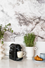 Automatic coffee maker machine and cup with cappuccino on kitchen table