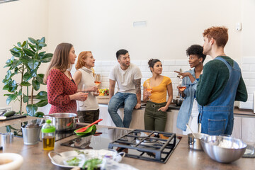Diverse Friends Chatting And Having A Glass Of Wine In The Kitchen.