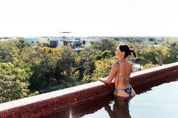 Slim woman in bikini standing on poolside