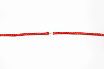 Red rope cut into two parts on a white isolated background. The concept of breaking human relationships or problems in business. Red broken line in the form of a thread - obrazy, fototapety, plakaty