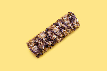 Muesli bar on a yellow background in the center. Whole grain energy bar with chocolate. Healthy...