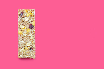 Muesli bar on a pink bright background. Healthy sweet dessert snack. Cereal muesli with nuts, oatmeal and berries on a pink background. Delicious and healthy dessert. Free space for text