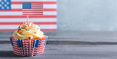 Tasty patriotic cupcake on wooden table against USA flag. American Independence Day
