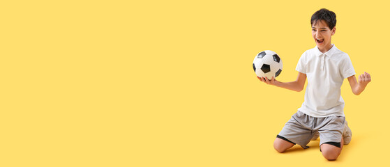 Fototapeta na wymiar Happy little boy holding soccer ball on yellow background with space for text
