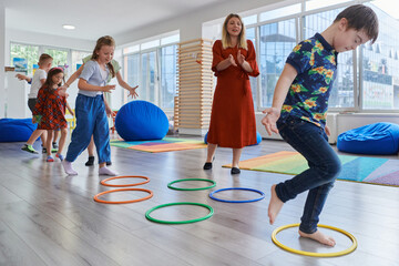 Small nursery school children with female teacher on floor indoors in classroom, doing exercise....