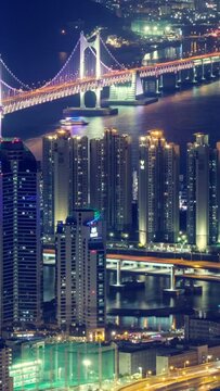 Busan, South Korea downtown cityscape with Gwangan Bridge aerial view timelapse at night. With horizontal panning motion