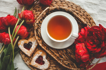 Tray with tasty breakfast, bouquet of peonies and gift for Valentine's Day on bed