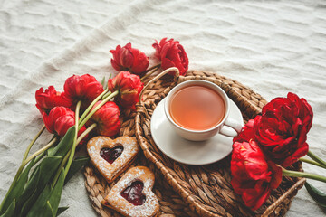 Tray with tasty breakfast, bouquet of peonies and gift for Valentine's Day on bed