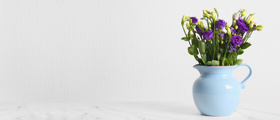 Jug with bouquet of eustoma flowers on light background with space for text