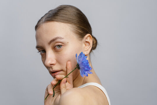 A woman poses in a studio with a flower