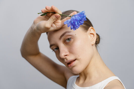 A woman poses in a studio with a flower