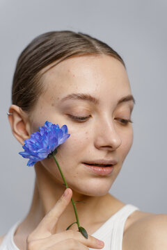 A woman poses in a studio with a flower