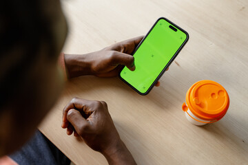 A mobile phone with a green screen in men's hands