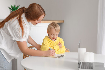 Mother and her little son drawing in notebook at home