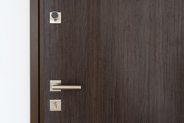 Closed brown wooden door with metal handle and keyhole