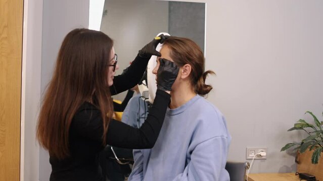 Eyebrow color, Eye beauty, Professional makeup. Beauty salon is working on eyebrows of young woman to correct their shape and add color.