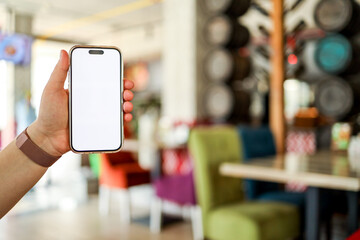The girl holds a phone in her hands with a blank isolated screen on the background of food in a restaurant. Place for your menu or review