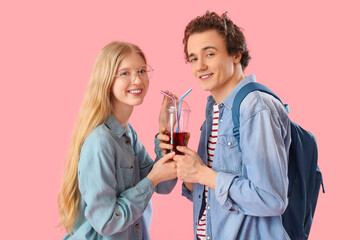 Teenage couple with glass of juice on pink background