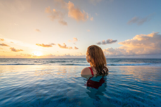 Woman Watching Colorful Tropical Sunrise Over Ocean in Infinity 
