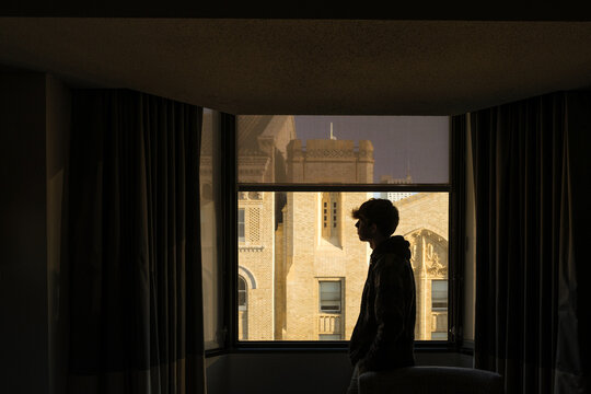 Silhouette of Teenager Standing in City Windwo