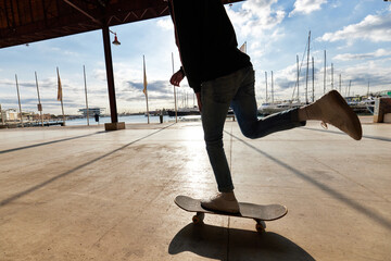 Cool young male skater riding on board at seaside