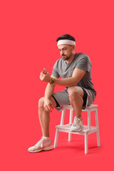 Sporty young man training on red background
