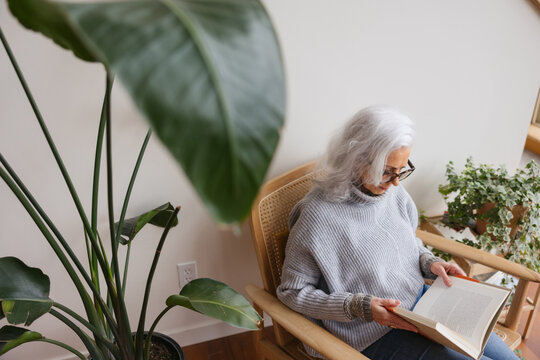 Woman reading in chair near window.