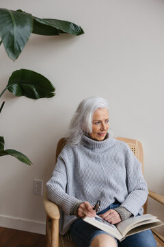 Woman reading in chair near window.